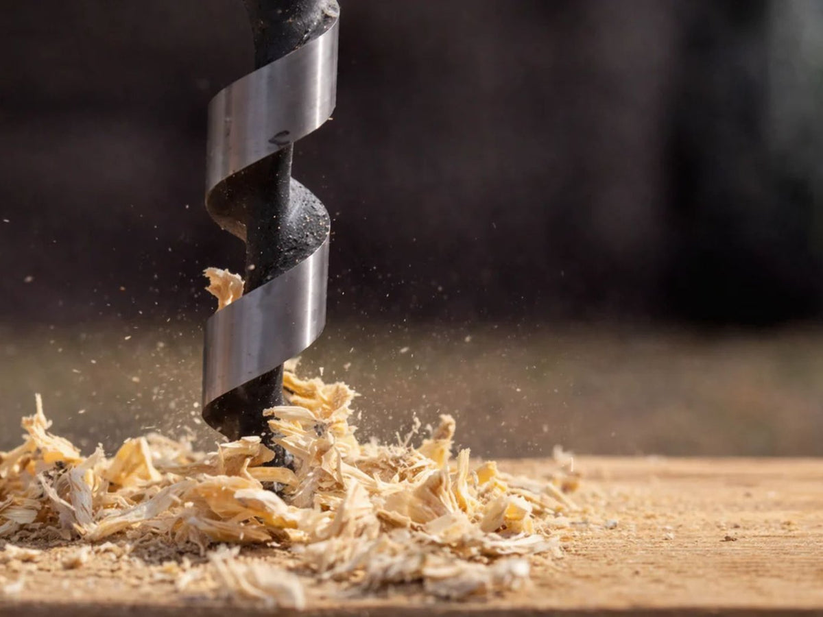 A concrete anchor bolt being drilled into a slab floor to secure a safe