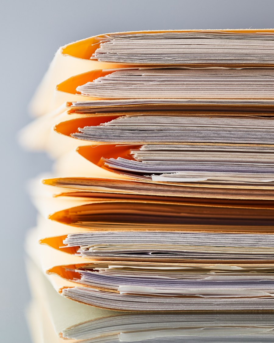 A tall stack of document files and paper folders lit from the side, representing the paper records a fire safe is built to protect