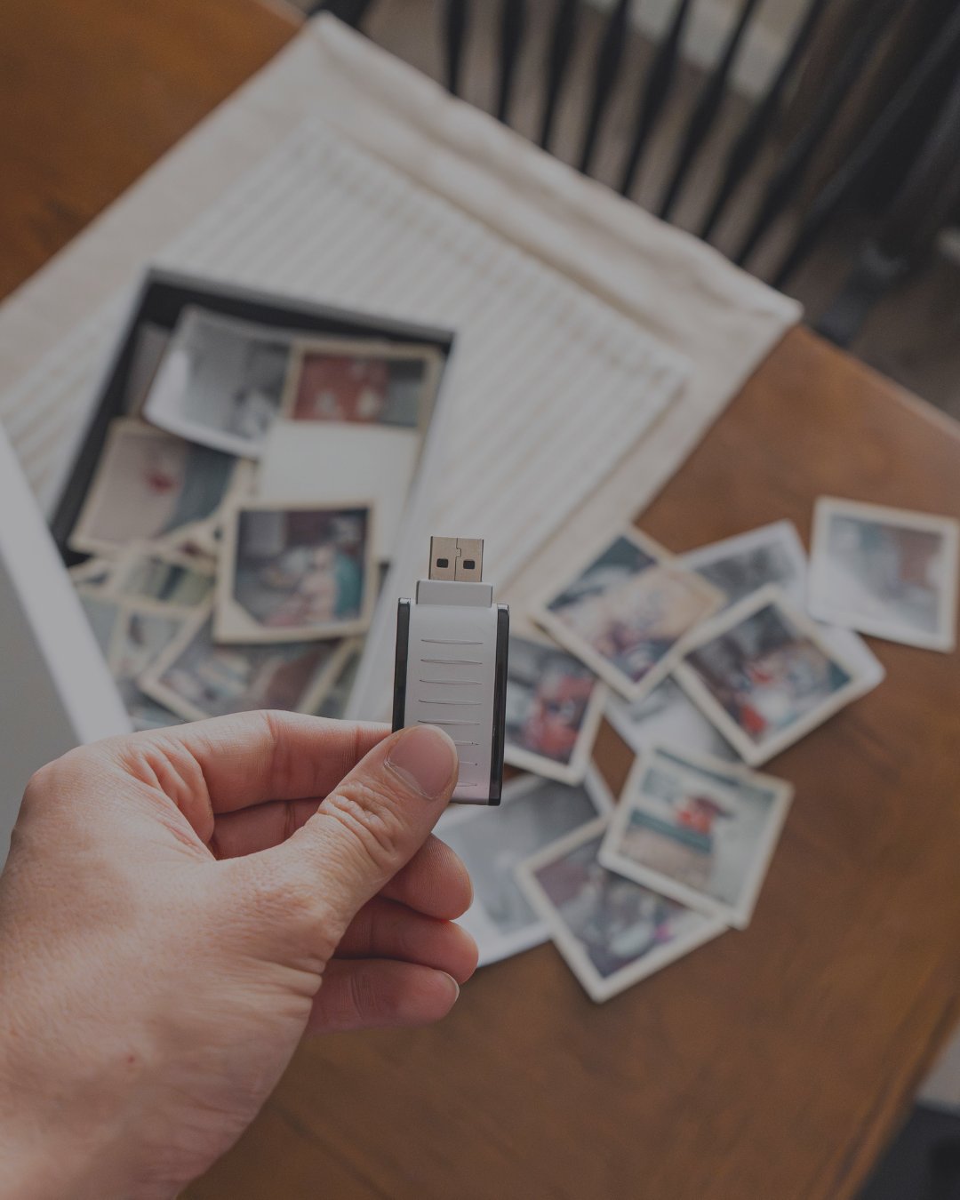 A row of USB flash drives and printed photographs beside a fire-rated media safe