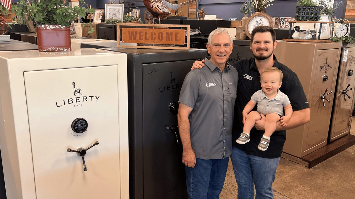 Dan and Kevin Engstrom with a grandchild in the Norcal Safe and Vault showroom, standing beside Liberty safes