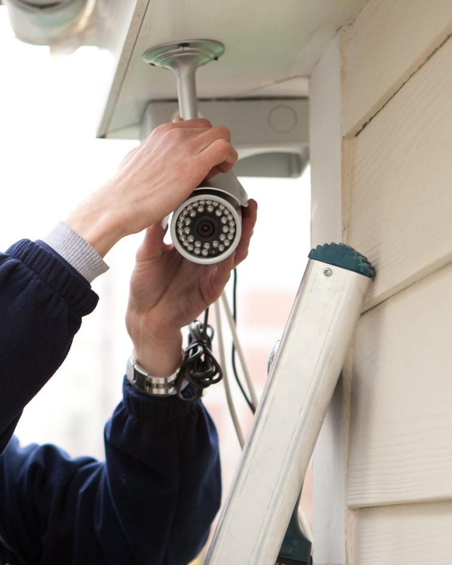 A technician installing an exterior home security camera, one layer of a complete protection plan