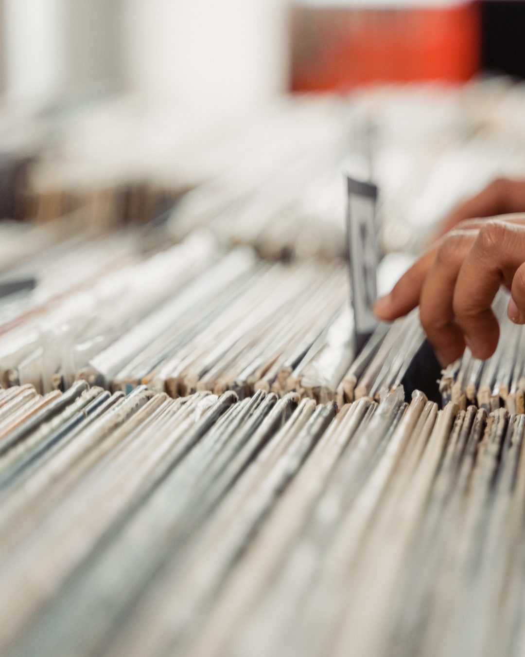 A hand flipping through densely packed rows of filed business records and documents
